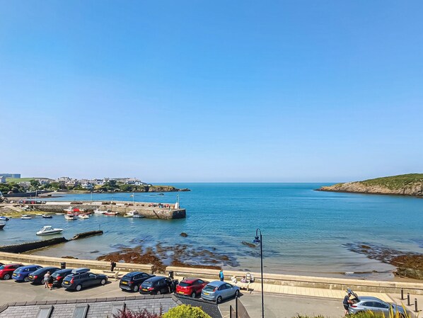 A coastal marina with parked cars and boats.