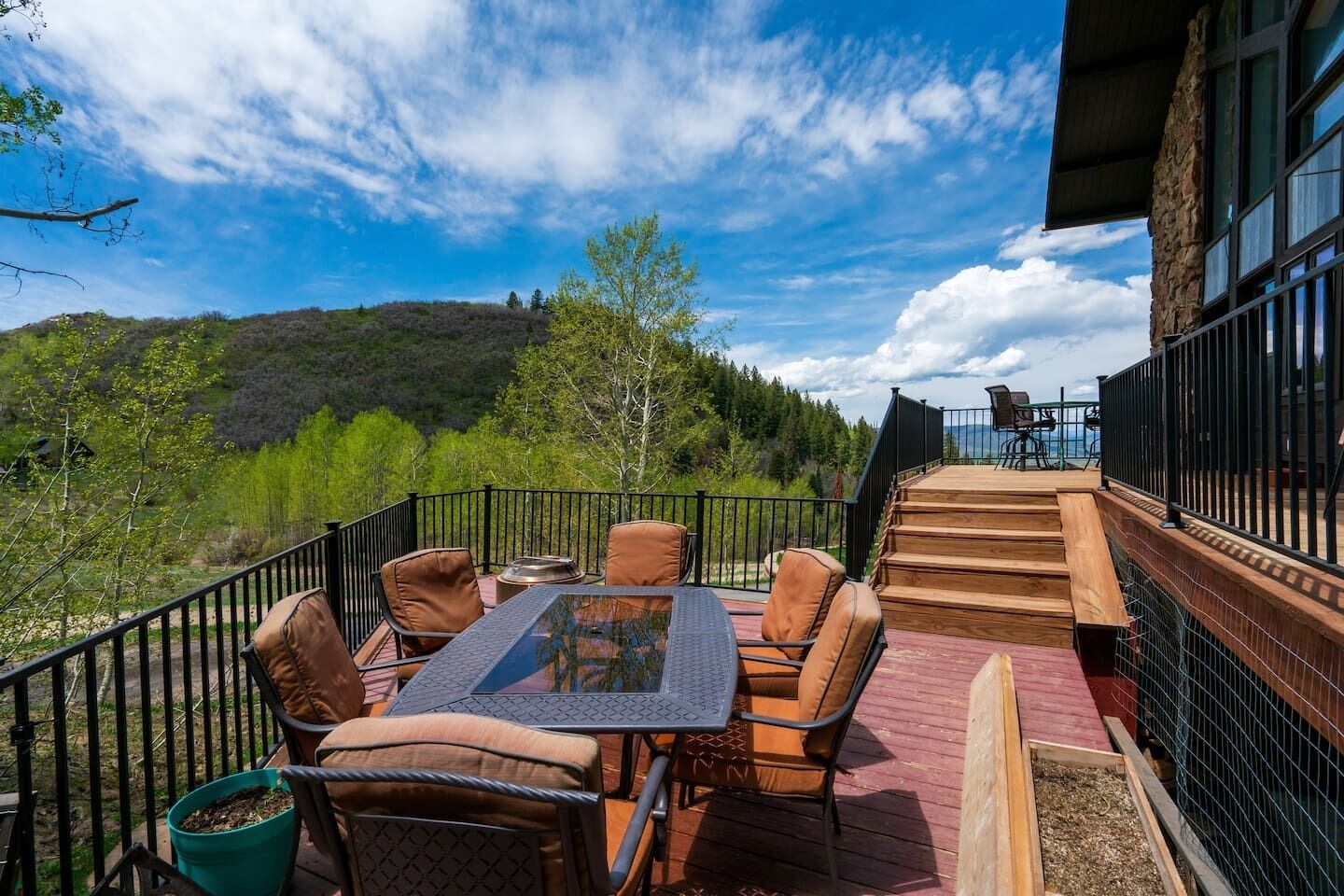 A deck with outdoor seating and a view of a forested hillside.