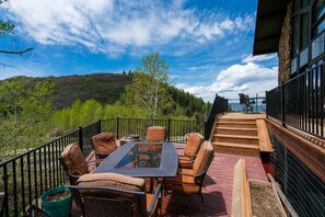 Una terraza con asientos al aire libre y vista a un paisaje boscoso.