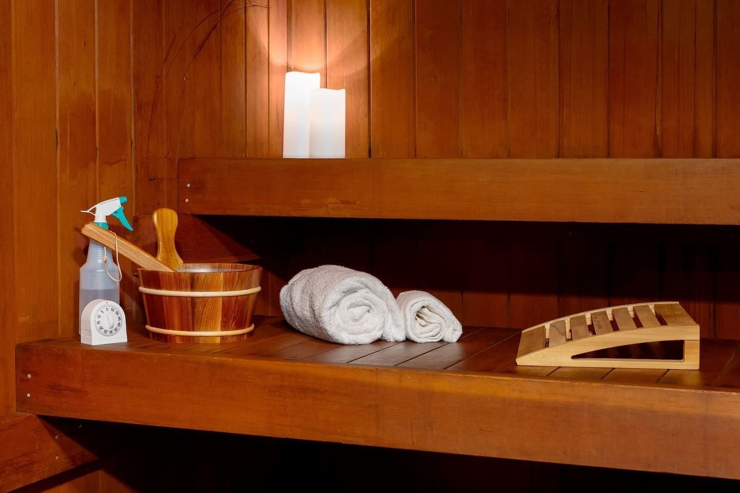 Eine Holzbank mit einem Handtuch, einem Holz-Eimer, einer Sprühflasche und einer Holzfußstütze.