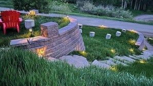A landscaped garden with a stone wall, red Adirondack chairs, and a pathway. - Private Luxury Mountain Estate w/ Views & Hot Tub (Steamboat Springs)