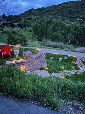 A landscaped garden with a stone wall, red Adirondack chairs, and a pathway. - Private Luxury Mountain Estate w/ Views & Hot Tub (Steamboat Springs)