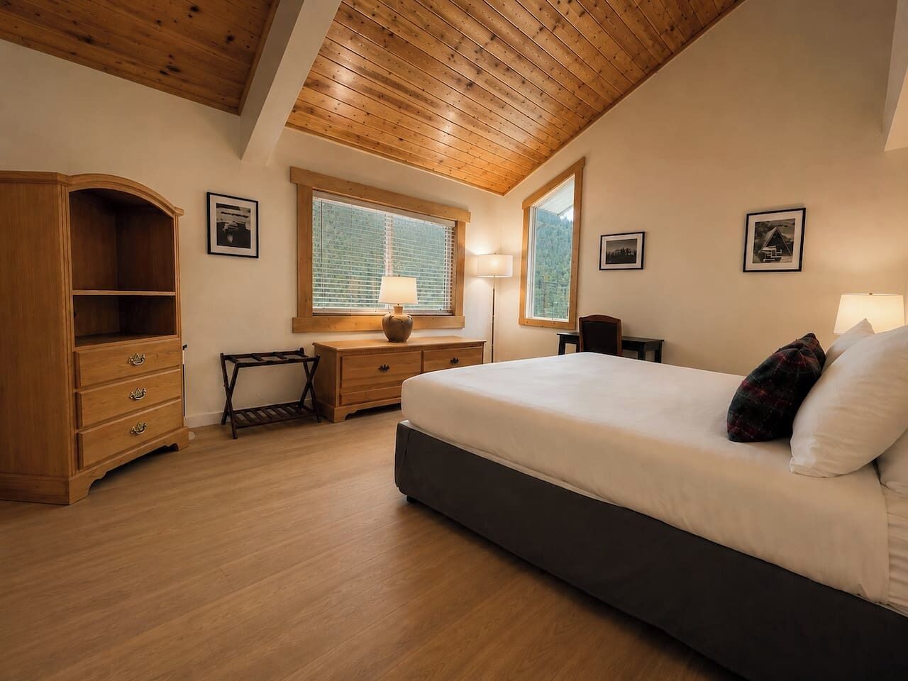 Ein Schlafzimmer mit einem großen Bett, Holzmöbeln, einem Schreibtisch und einem Fenster mit Jalousien.