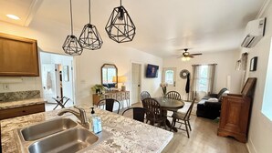 A kitchen with granite countertops, stainless steel sinks, and pendant lighting. There is a dining area with a table and chairs. - Spacious 3 Bedroom Home with yard, pet friendly & sleeps 6! (Oroville)