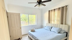 A bedroom with a bed, a ceiling fan, a window, and a door. - Spacious 3 Bedroom Home with yard, pet friendly & sleeps 6! (Oroville)