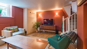 Un salon avec un canapé, une table basse, un téléviseur et un escalier.