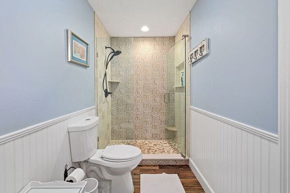 A bathroom with a toilet, shower, and a tiled floor. - Pool Home Walk to Beach | Good Morning Rentals (Jacksonville Beach)