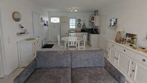 Ein kompakter Wohnraum mit Sofa, Esstisch, Küchenzeile und kleinem Balkon.