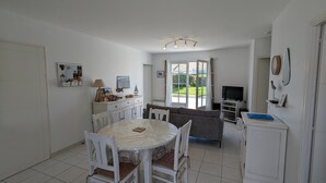 Ein geräumiger Wohnbereich mit Esstisch, Stühlen, einer Couch und einem Fernseher.