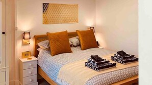 A bedroom with a bed, bedside tables, a nightstand, a wall-mounted lamp, and a decorative ceiling light. - SHINE CHALET - UNIQUE & COMFORTABLE ACCOMMODATION (REDRUTH)