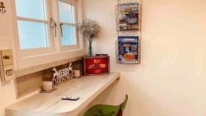 A kitchen with a white countertop, two bar stools, a window, and a wall-mounted poster. - SHINE CHALET - UNIQUE & COMFORTABLE ACCOMMODATION (REDRUTH)