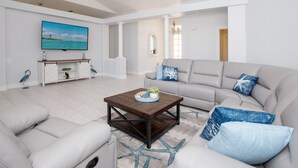 A modern living room with a sofa, coffee table, and a TV mounted on the wall. - Prestige Waterfront Paradise: Sunset Views, Private Pool & Boat Rental Option! (Cape Coral)
