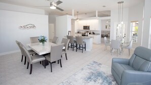 A modern kitchen with white cabinets, a microwave, and a dining area with a marble table and chairs. - Prestige Waterfront Paradise: Sunset Views, Private Pool & Boat Rental Option! (Cape Coral)