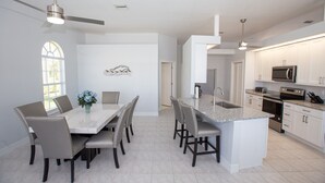 A modern kitchen with white cabinets, a granite countertop, and stainless steel appliances. - Prestige Waterfront Paradise: Sunset Views, Private Pool & Boat Rental Option! (Cape Coral)