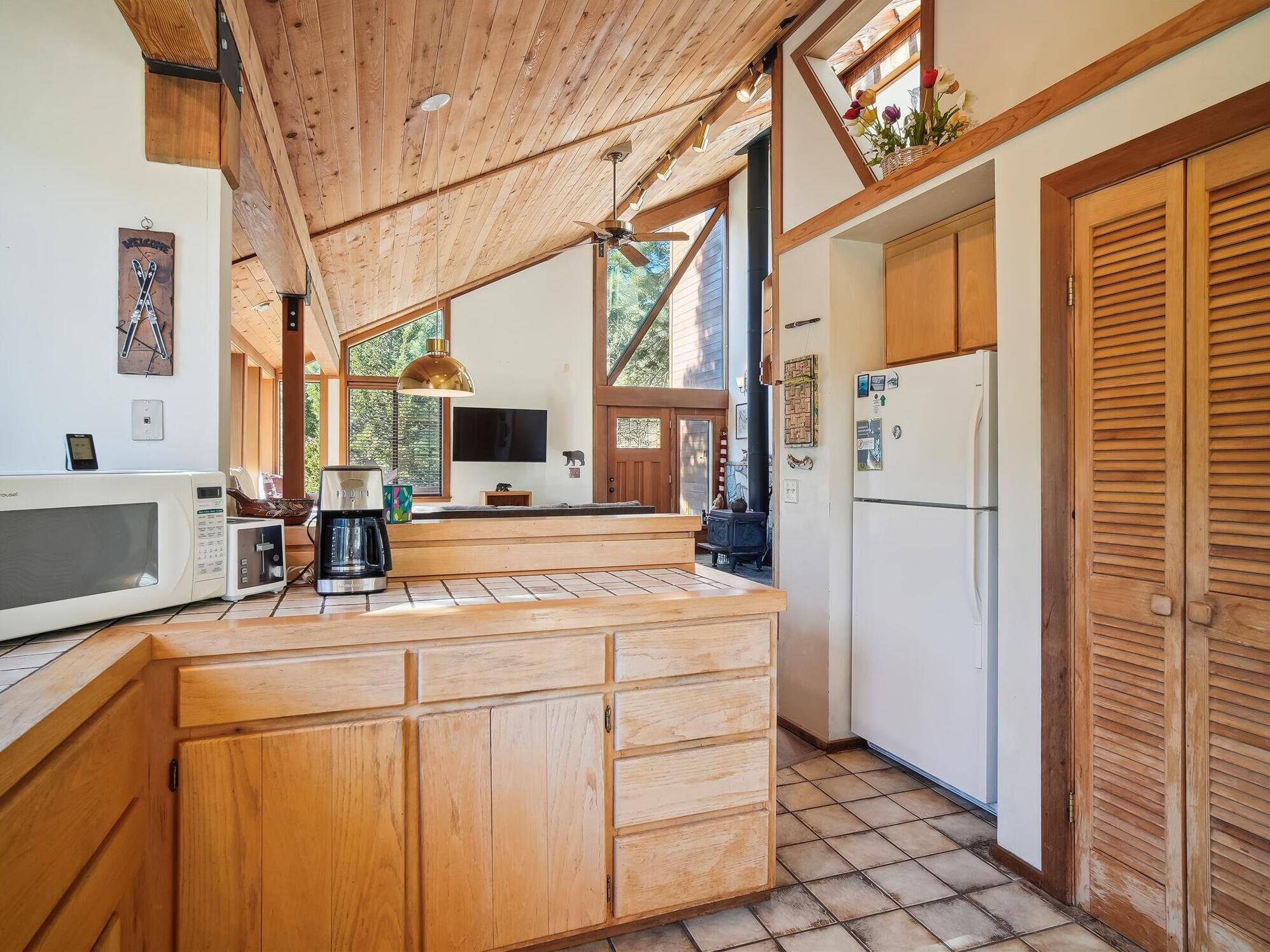 Una cocina con armarios de madera, microondas, cafetera y estufa.