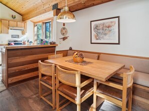 A wooden dining table with a bench, surrounded by wicker chairs.