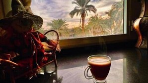 Una mesa con una taza de café y una figurita de bruja.