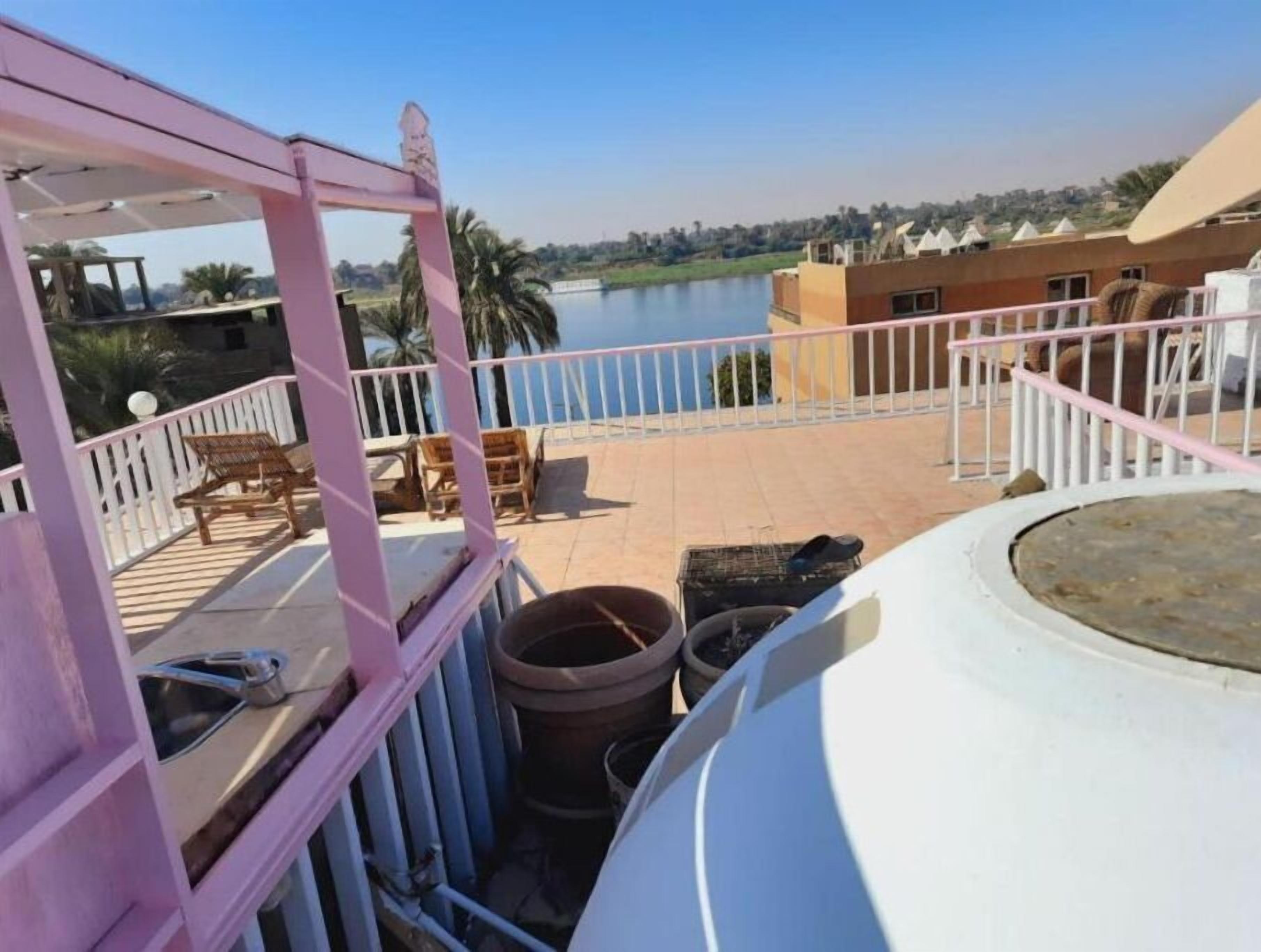 Varanda com vista para um lago, mobiliário de exterior e corrimão branco.