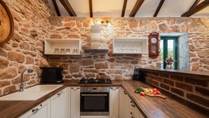 Una cocina rústica con paredes de piedra, vigas de madera, estufa empotrada y ventana con vistas.