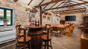 Un interior rústico con paredes de piedra, vigas de madera y una mesa redonda de madera con sillas.