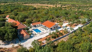 Vista aérea de una propiedad con varias construcciones, una piscina y zonas verdes circundantes.