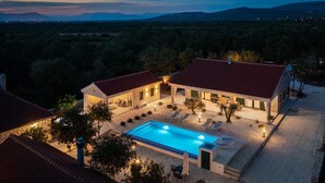 Una casa de dos plantas con piscina, mobiliario exterior y vistas del paisaje circundante.