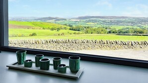 A window with a view of a green landscape, stone wall, and a tray with green cups. - 2 bedroom accommodation in Carleton, near Skipton (Carleton, near Skipton)