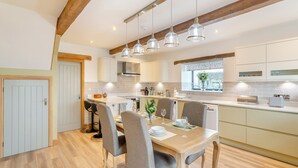 A modern kitchen with wooden beams, a dining area with four chairs, and a window with a view. - 2 bedroom accommodation in Carleton, near Skipton (Carleton, near Skipton)
