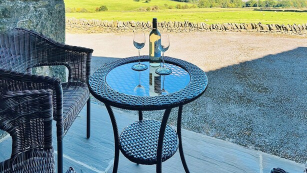 A round table with two chairs on a balcony overlooking a rural landscape. - 2 bedroom accommodation in Carleton, near Skipton (Carleton, near Skipton)