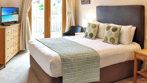 A hotel room with a bed, a TV on a dresser, a desk, and a chair.