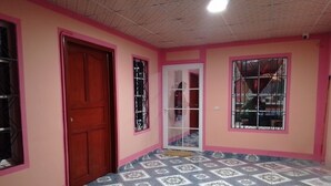 A room with pink walls, a wooden door, and patterned floor tiles.