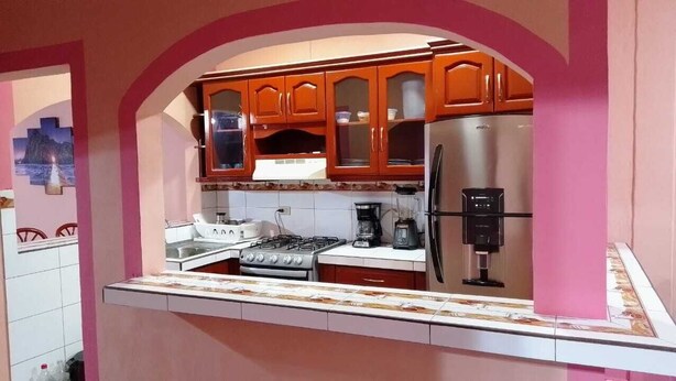 A kitchen with wooden cabinets, a stainless steel refrigerator, a gas stove, and a coffee maker.