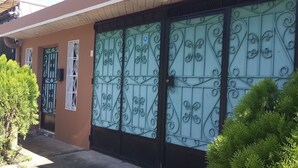 A building with ornate metal gates, a small tree, and a parked car.