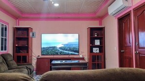 A living room with a television, two sofas, and a wooden cabinet.