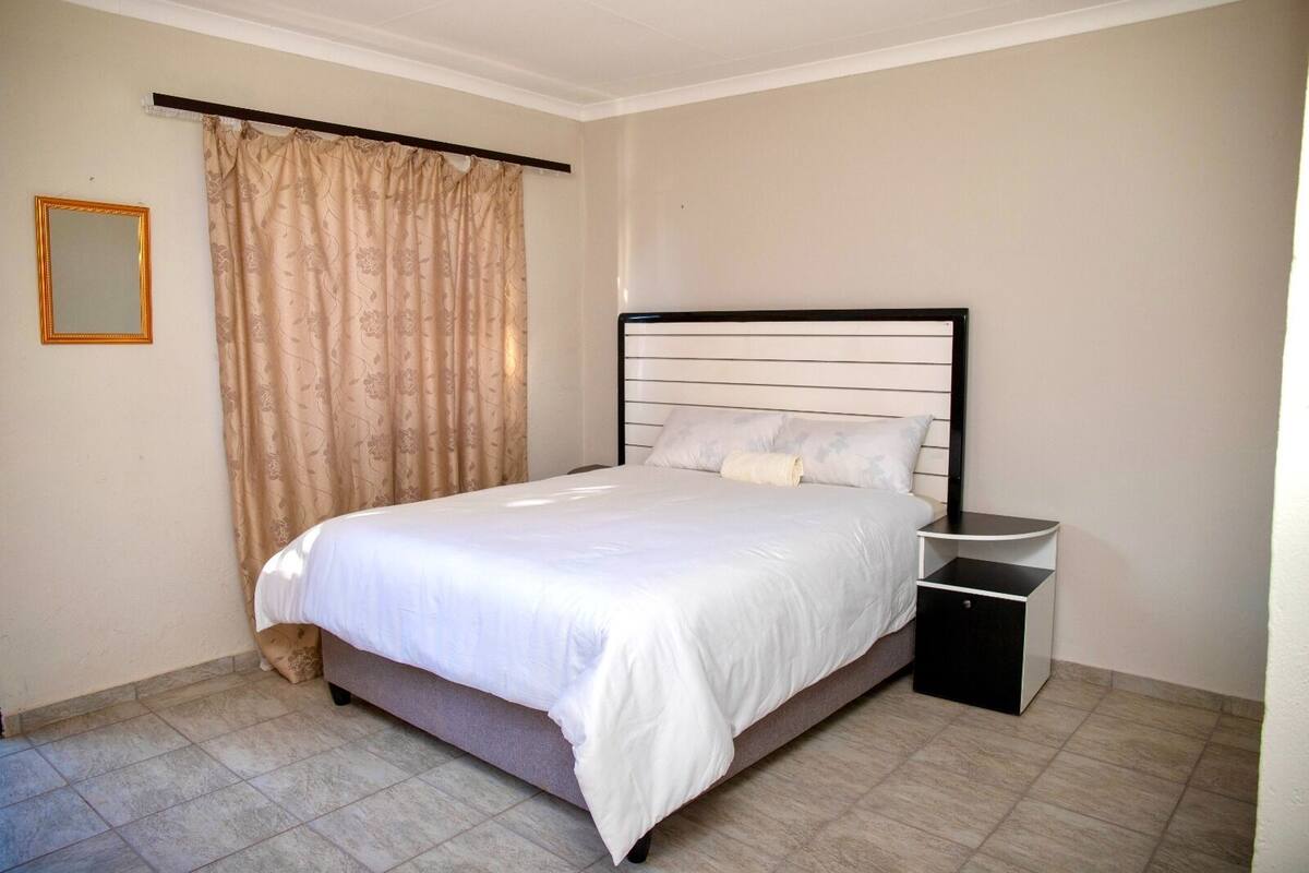 A bedroom with a bed, a nightstand, and a mirror.
