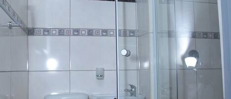 A bathroom with a toilet, sink, and glass shower enclosure.