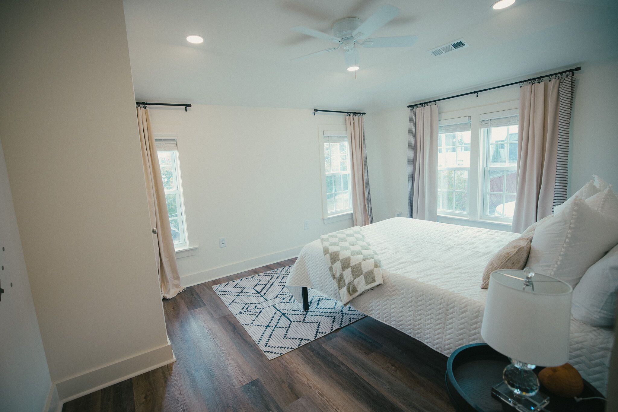 A bedroom with a large bed, a ceiling fan, and a window with curtains.