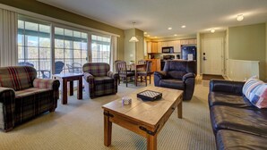 A living room with a sofa, chairs, a coffee table, and a view of the kitchen. - Fairway to Heaven at Shanty Creek (Bellaire)