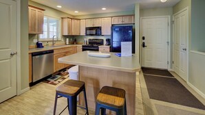 A kitchen with wooden cabinets, a stainless steel dishwasher, a refrigerator, and a microwave. - Fairway to Heaven at Shanty Creek (Bellaire)