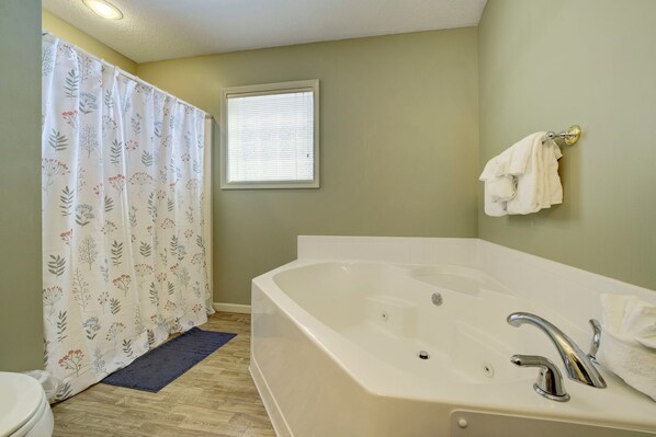 A bathroom with a bathtub, a shower curtain, a window, and a towel rack. - Fairway to Heaven at Shanty Creek (Bellaire)