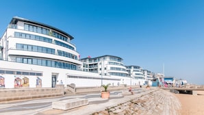 Un hôtel situé au bord de l’eau, composé de plusieurs bâtiments blancs, doté d’une promenade et d’une plage.