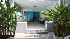 Une entrée moderne avec des portes en verre, un intérieur bleu et des plantes en pot.