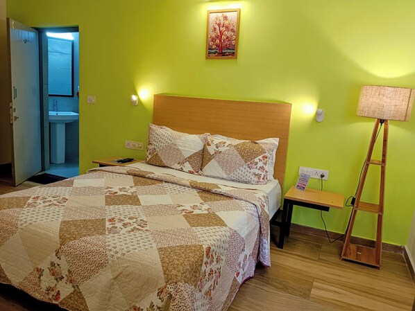 A bedroom with a bed, a bedside table, a lamp, and a painting on the wall.
