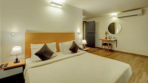 Une chambre d’hôtel avec un grand lit, des lampes de chevet, un bureau avec une chaise, un miroir et un appareil de climatisation.