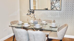 Un'area pranzo con un tavolo in vetro, quattro sedie e un vaso con fiori.