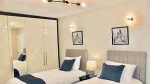 Una camera d'albergo con due letti, un armadio e due lampade a parete.