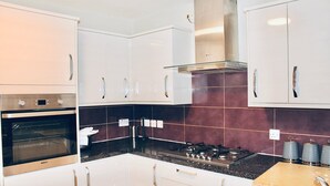 Una cucina moderna con mobili bianchi, una cappa in acciaio inossidabile e un piano di lavoro nero.