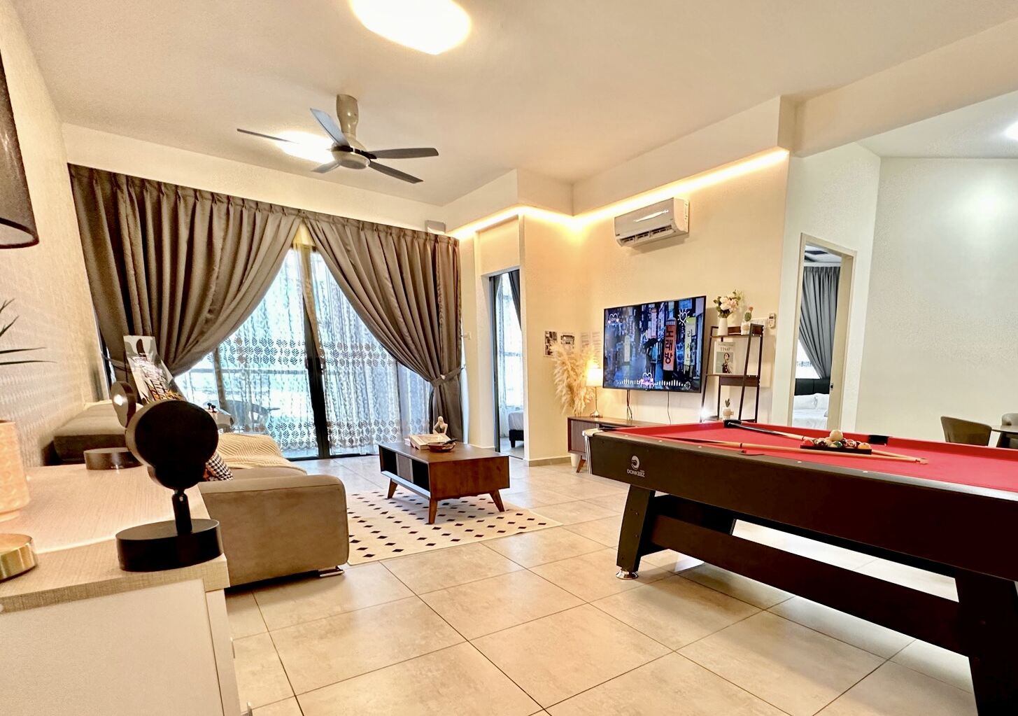 A modern living room with a pool table, a sofa, a television, and a ceiling fan.