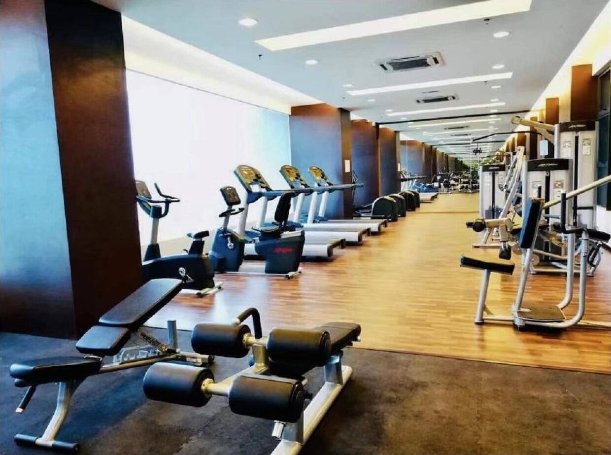 A gym with cardio machines, weight benches, and free weights.