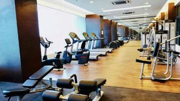 A gym with cardio machines, weight benches, and free weights.